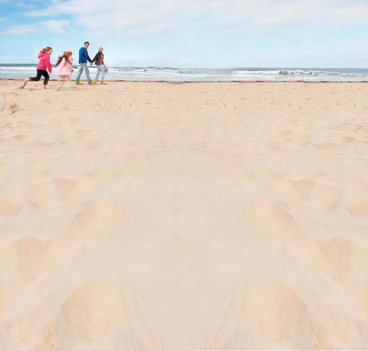 Gezin wandelt over het Noordzeestrand in Zeeland